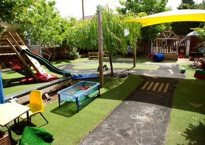 Garden in Cambridge nursery, slide, astro turf with a road and outside toys.