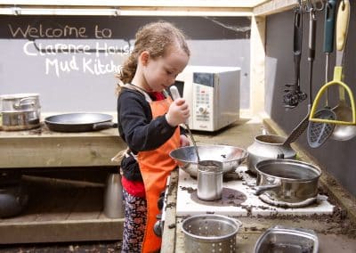 Girl playing with mud kitchen in the garden of Chatteris nursery
