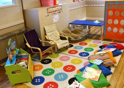 Quiet area with chairs, rugs and floor cushion and a display of books in Godmanchester preschool